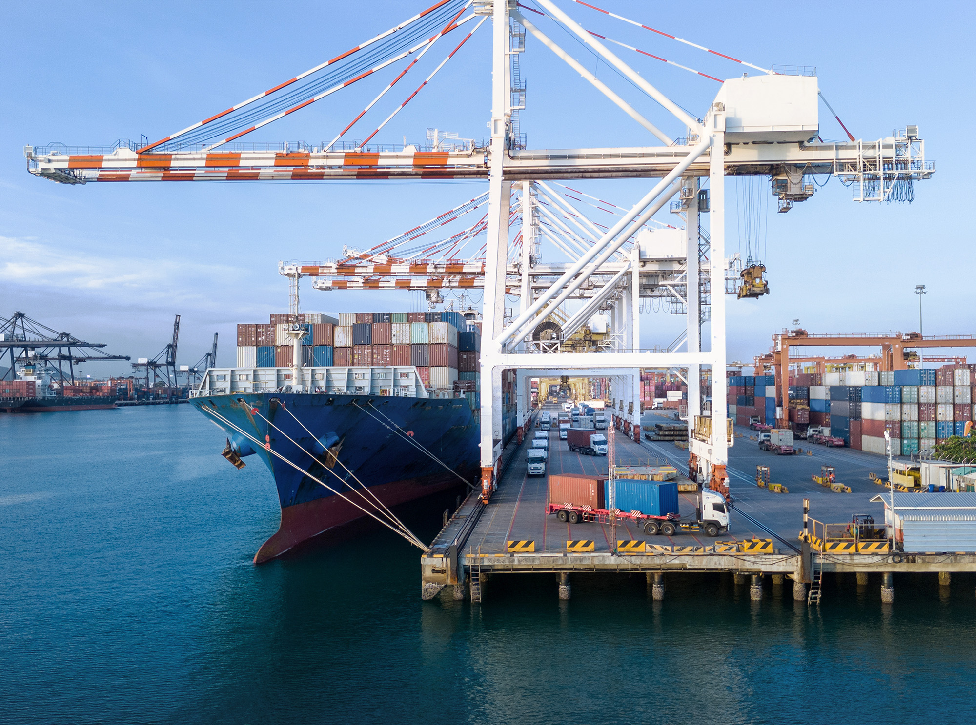 Großes Containerschiff wird per Kran in einem Hafen beladen